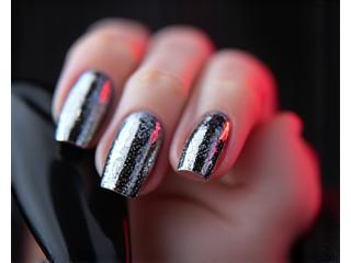 Gros plan sur des ongles avec nail art 'cat-eye' et effet chrome.